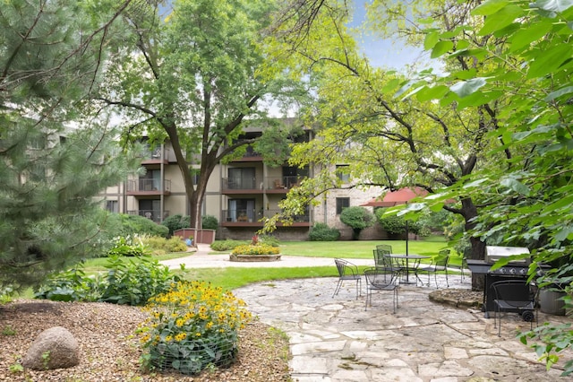 view of property's community featuring a patio area and a lawn