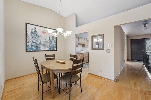 dining room with vaulted ceiling, sink, a notable chandelier, and light wood-type flooring