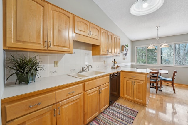 kitchen featuring lofted ceiling, sink, decorative light fixtures, dishwasher, and light hardwood / wood-style floors