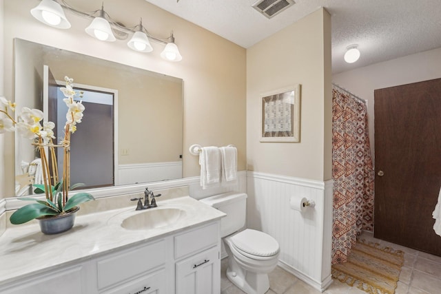 bathroom with vanity, toilet, tile patterned flooring, and a textured ceiling