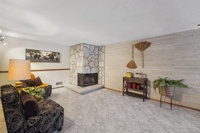 carpeted living room with a textured ceiling and a fireplace