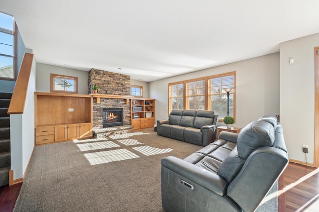 living area with baseboards, a fireplace, and stairway