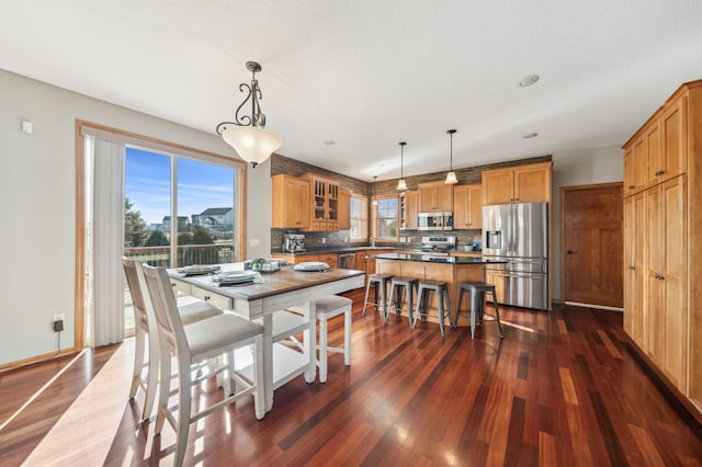 dining area with dark wood finished floors, plenty of natural light, and baseboards