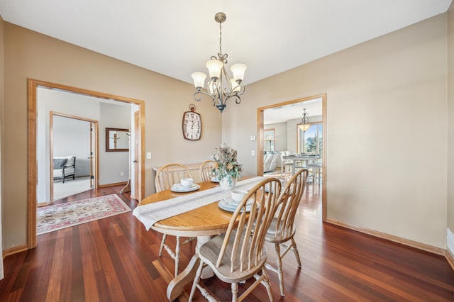 dining room featuring dark wood-style floors, baseboards, and a chandelier