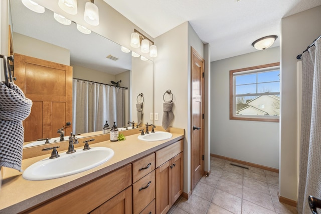 bathroom with visible vents, a sink, baseboards, and double vanity