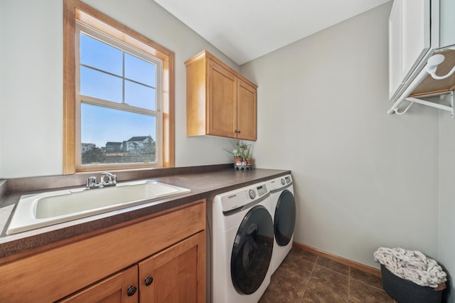 clothes washing area featuring baseboards, a sink, cabinet space, and washer and dryer