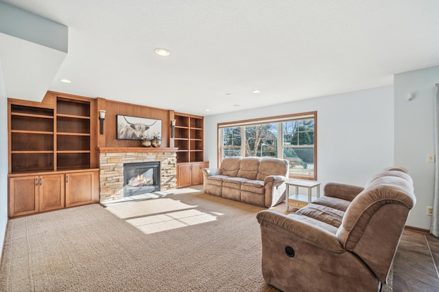 living area featuring built in features, recessed lighting, dark carpet, and a fireplace