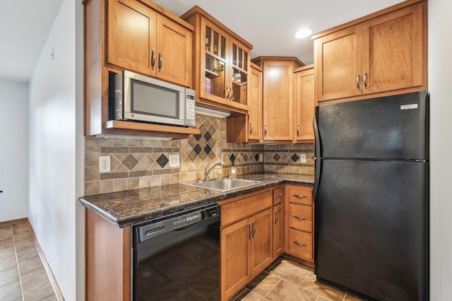 kitchen featuring light tile patterned floors, glass insert cabinets, a sink, black appliances, and backsplash