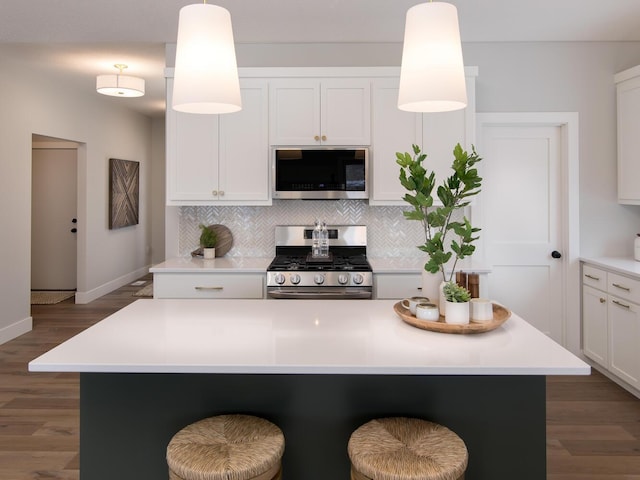 kitchen featuring a kitchen island, appliances with stainless steel finishes, pendant lighting, white cabinetry, and backsplash