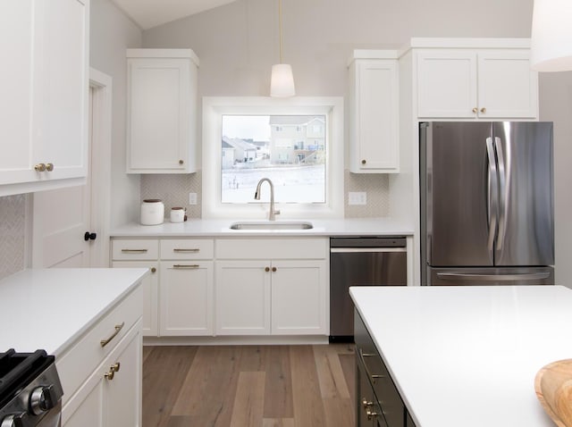 kitchen featuring sink, hanging light fixtures, appliances with stainless steel finishes, white cabinets, and backsplash