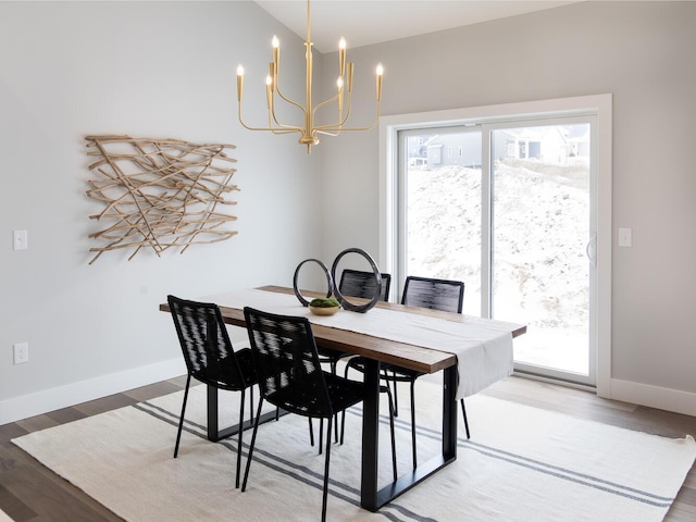 dining room with hardwood / wood-style flooring, vaulted ceiling, and a notable chandelier