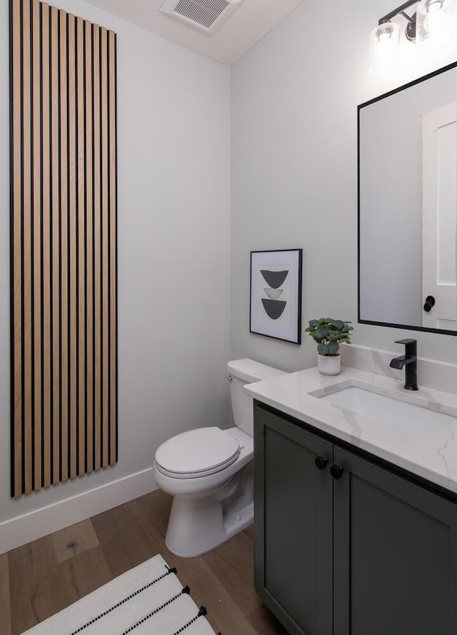 bathroom with wood-type flooring, vanity, and toilet