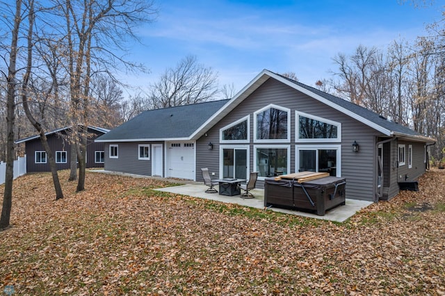 rear view of property with a hot tub and a patio area