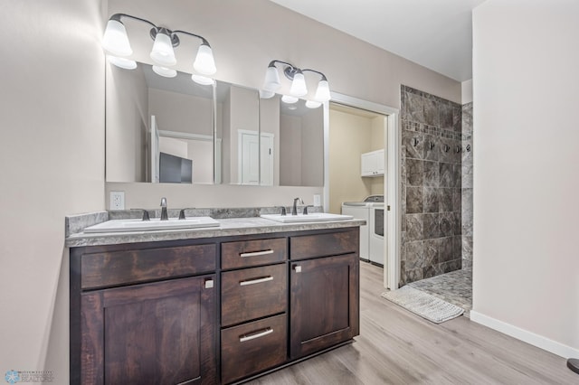 bathroom with hardwood / wood-style flooring, independent washer and dryer, vanity, and a tile shower