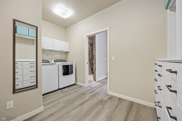 washroom with cabinets, washing machine and dryer, and light hardwood / wood-style flooring