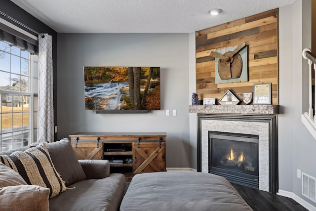 living room featuring a stone fireplace, a textured ceiling, and dark hardwood / wood-style flooring