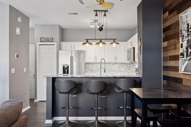 kitchen featuring light stone counters, tasteful backsplash, appliances with stainless steel finishes, pendant lighting, and white cabinets