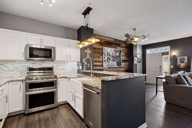 kitchen featuring sink, appliances with stainless steel finishes, white cabinetry, dark hardwood / wood-style floors, and decorative light fixtures