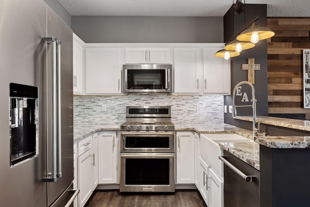 kitchen featuring appliances with stainless steel finishes, decorative light fixtures, light stone countertops, and white cabinets