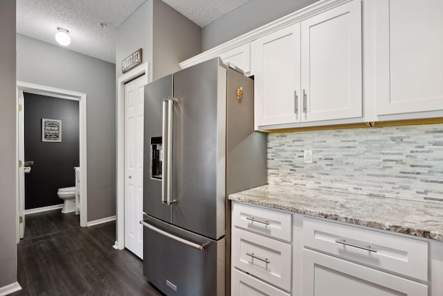 kitchen featuring white cabinetry, high end fridge, and light stone countertops