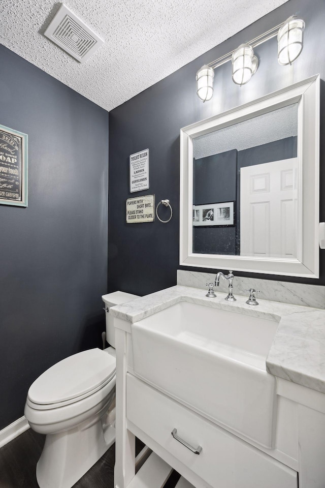 bathroom featuring vanity, hardwood / wood-style floors, a textured ceiling, and toilet