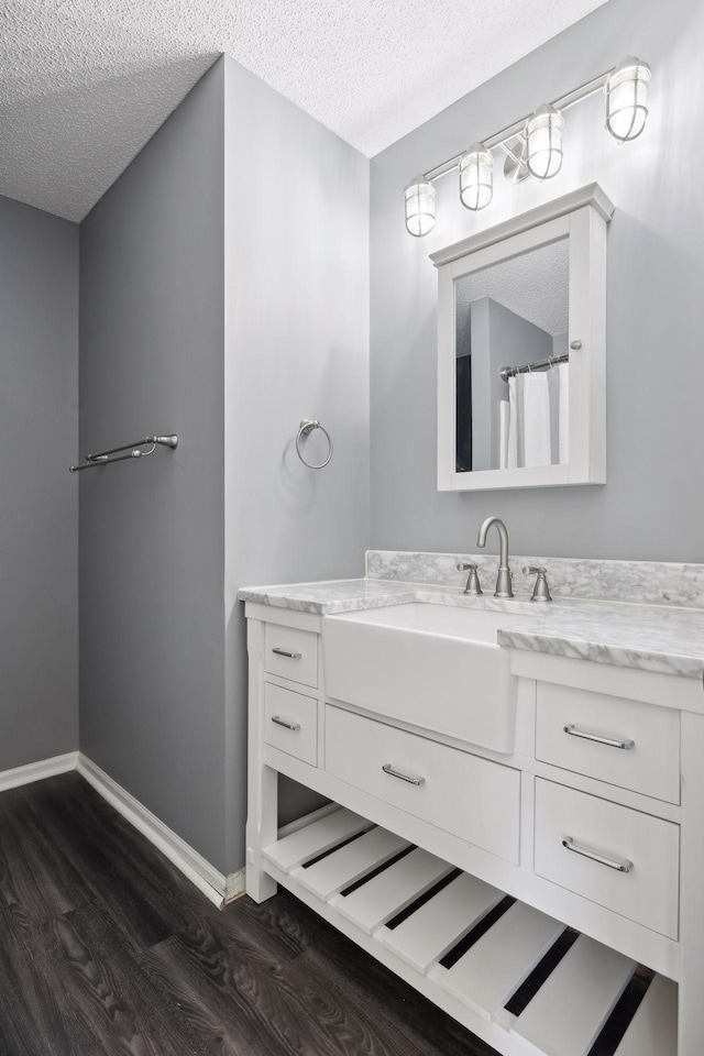 bathroom featuring vanity, curtained shower, hardwood / wood-style floors, and a textured ceiling