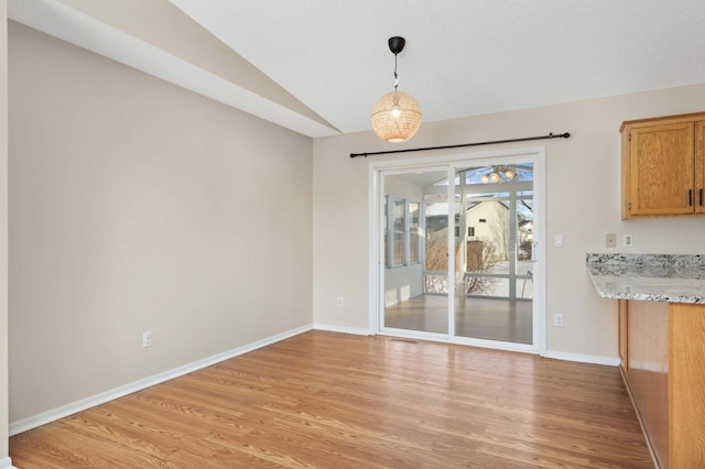 unfurnished dining area with light hardwood / wood-style floors and vaulted ceiling