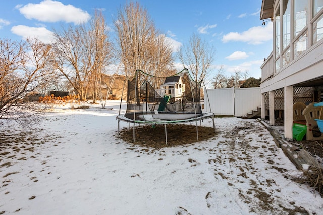 yard covered in snow with a trampoline