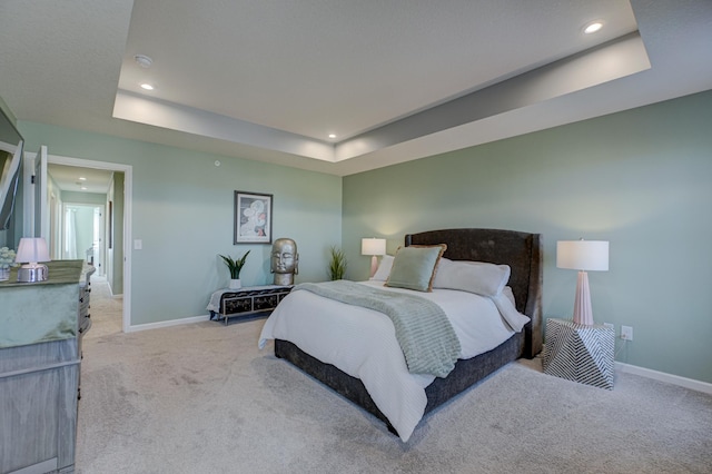 bedroom with a tray ceiling and light carpet