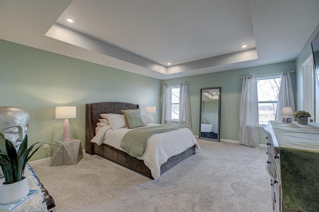 carpeted bedroom featuring a raised ceiling and multiple windows