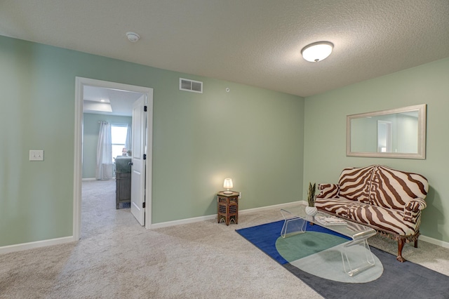 sitting room with light colored carpet and a textured ceiling