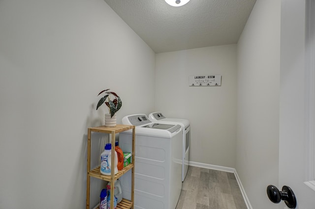 washroom featuring washing machine and dryer, light hardwood / wood-style floors, and a textured ceiling