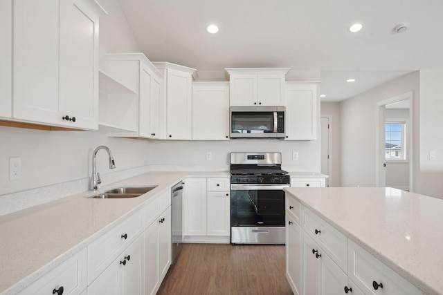 kitchen with stainless steel appliances, sink, white cabinets, and light stone counters