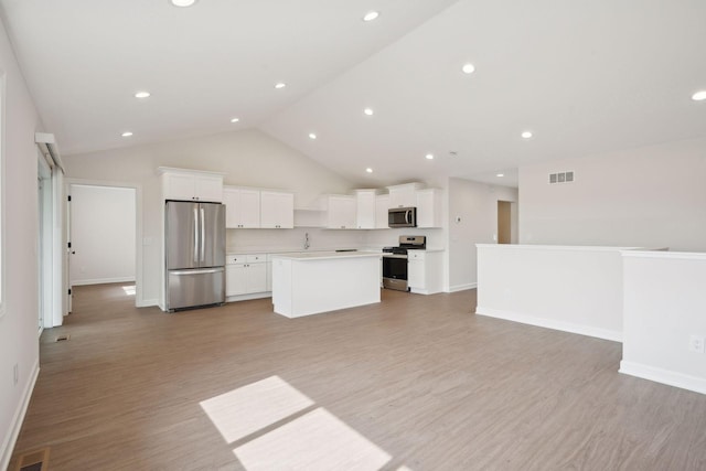 kitchen with stainless steel appliances, a kitchen island, white cabinets, and light wood-type flooring