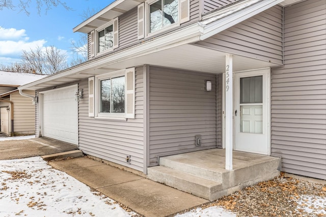 snow covered property entrance with a garage