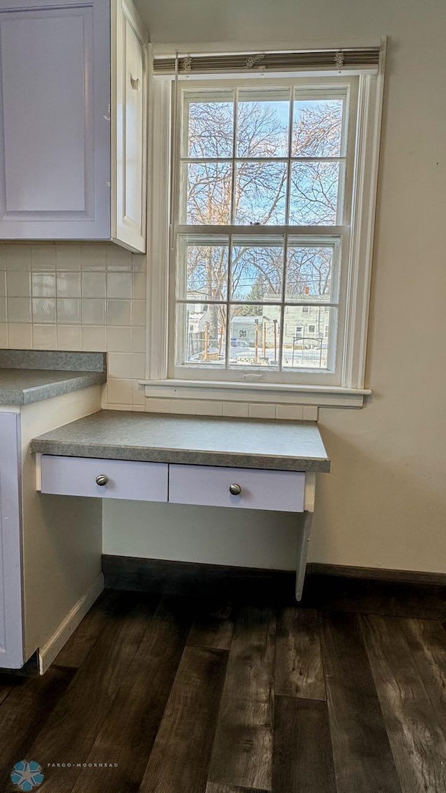 interior details with tasteful backsplash, dark wood-type flooring, and white cabinets