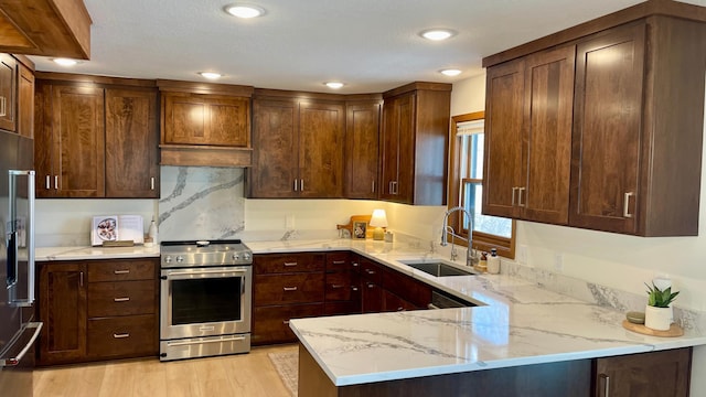 kitchen with sink, light hardwood / wood-style flooring, high end appliances, light stone countertops, and kitchen peninsula