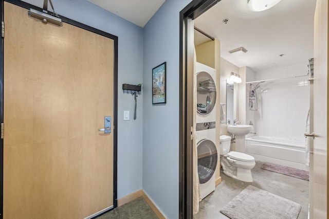 bathroom featuring concrete flooring, stacked washing maching and dryer, toilet, and tiled shower / bath