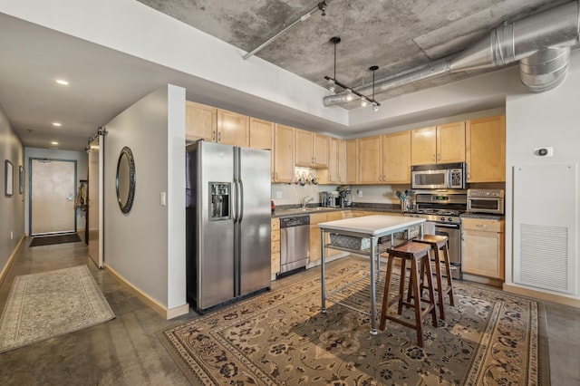 kitchen with appliances with stainless steel finishes, a barn door, light brown cabinetry, and sink