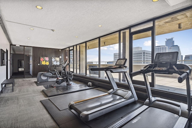 exercise room featuring dark colored carpet, a textured ceiling, and wood walls