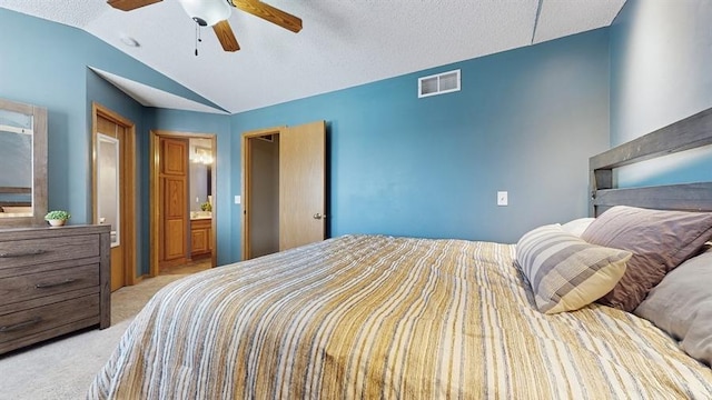 carpeted bedroom with visible vents, ceiling fan, ensuite bathroom, and vaulted ceiling