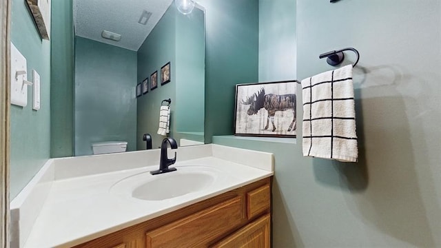 bathroom with toilet, a textured ceiling, and vanity