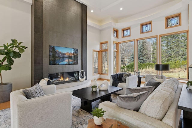 living area featuring recessed lighting, a large fireplace, plenty of natural light, and a towering ceiling