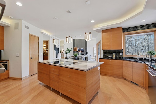 kitchen with light wood-style flooring, modern cabinets, black electric stovetop, stainless steel dishwasher, and a sink