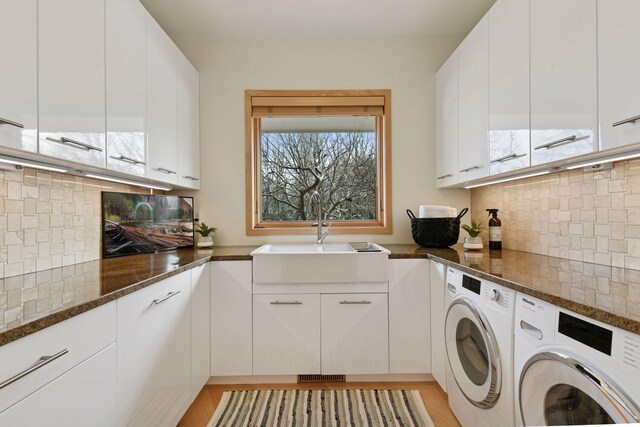 laundry room with cabinet space, a sink, and washer and clothes dryer