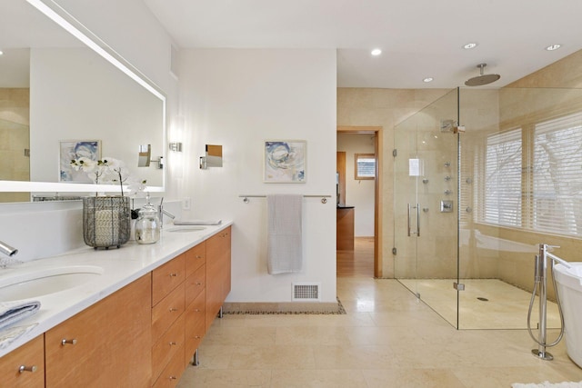 bathroom featuring visible vents, a sink, a shower stall, and double vanity