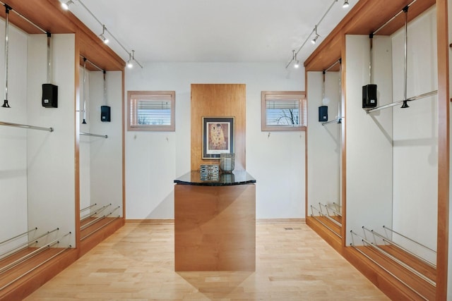 corridor with rail lighting and light wood-style flooring