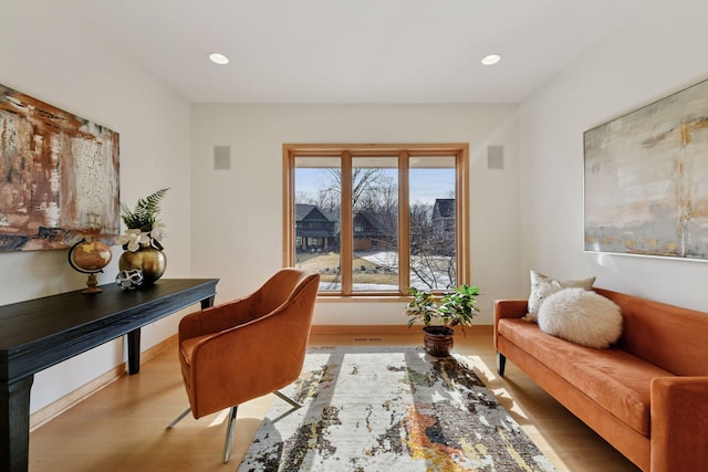 sitting room with baseboards, wood finished floors, and recessed lighting