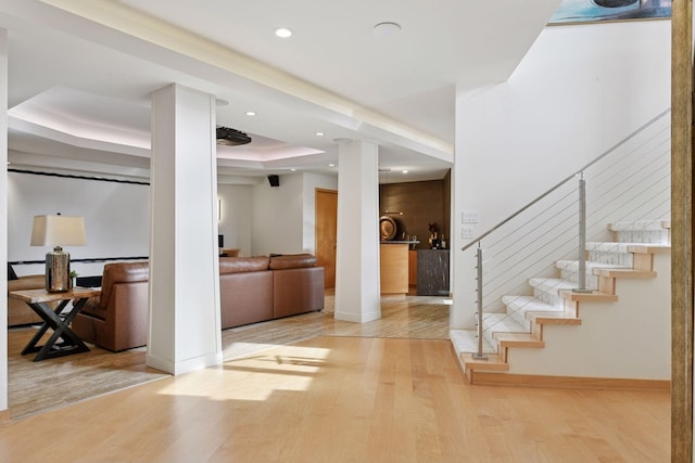 foyer featuring recessed lighting, wood finished floors, baseboards, stairway, and a tray ceiling