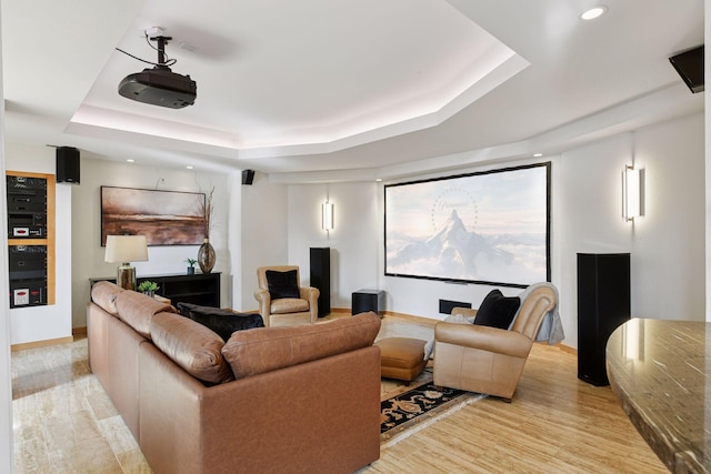 cinema featuring light wood-type flooring, a tray ceiling, and recessed lighting